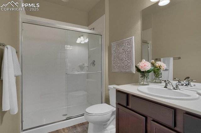 bathroom featuring vanity, a shower with shower door, wood-type flooring, and toilet