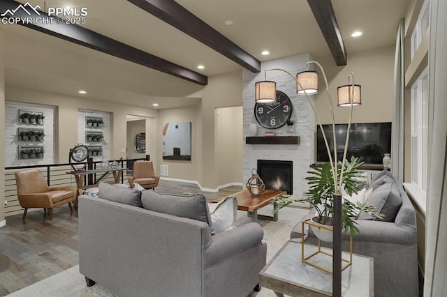 living room with beamed ceiling, a large fireplace, and hardwood / wood-style floors