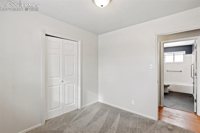 unfurnished bedroom featuring light carpet, a closet, and ensuite bathroom