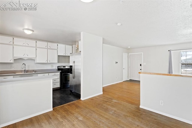 kitchen featuring sink, stainless steel appliances, a textured ceiling, white cabinets, and light wood-type flooring