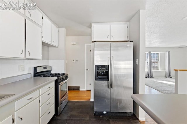 kitchen featuring white cabinetry, backsplash, dark wood-type flooring, and appliances with stainless steel finishes