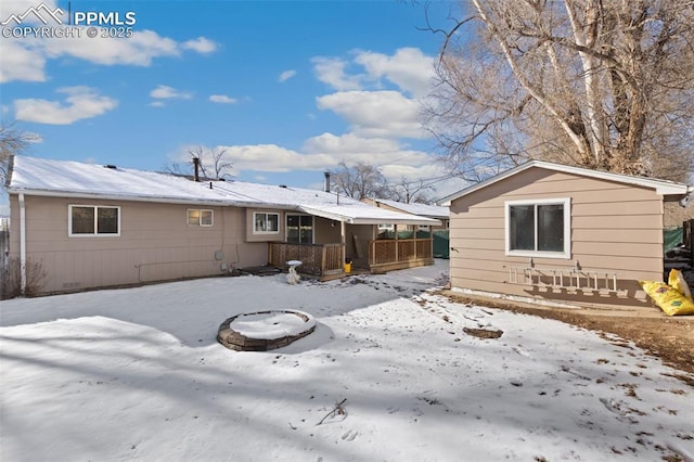 snow covered rear of property with a fire pit and covered porch