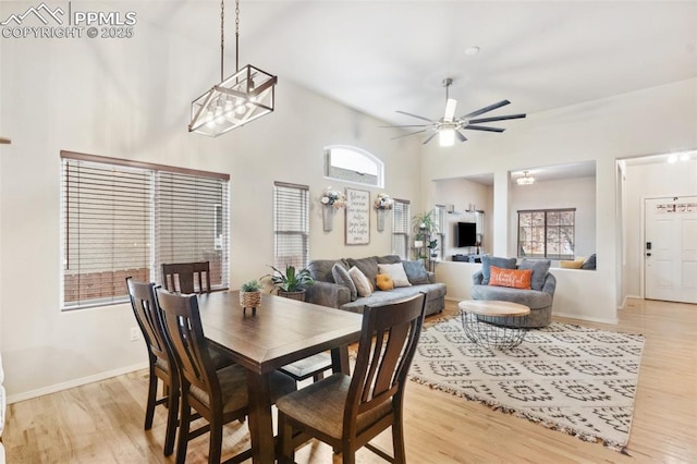 dining room with light hardwood / wood-style flooring, ceiling fan, and a high ceiling