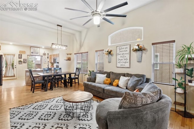 living room featuring ceiling fan, plenty of natural light, light hardwood / wood-style flooring, and a high ceiling