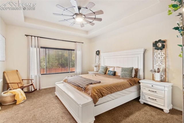 bedroom featuring ceiling fan, a tray ceiling, and light carpet