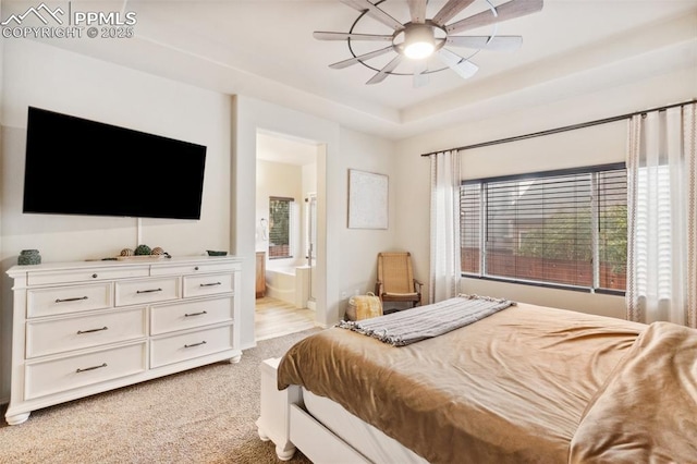 carpeted bedroom featuring ceiling fan, ensuite bathroom, and a raised ceiling