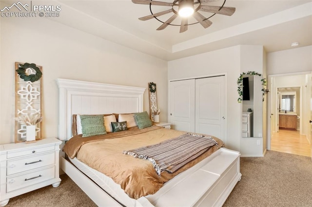 bedroom with a tray ceiling, carpet flooring, ceiling fan, and a closet