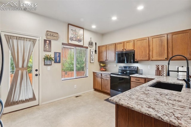 kitchen with light stone counters, sink, and stainless steel range with electric cooktop