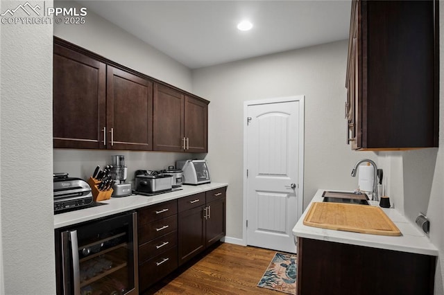 kitchen featuring wine cooler, sink, dark wood-type flooring, and dark brown cabinetry