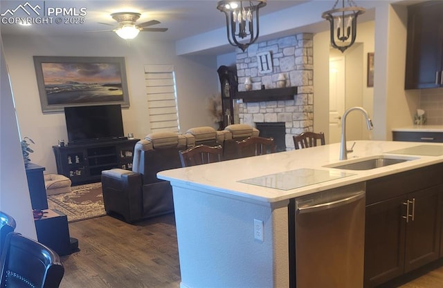 kitchen featuring dark wood-type flooring, sink, dishwasher, pendant lighting, and a fireplace