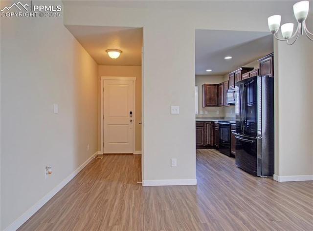 kitchen featuring dark brown cabinets, light hardwood / wood-style flooring, a notable chandelier, and black appliances