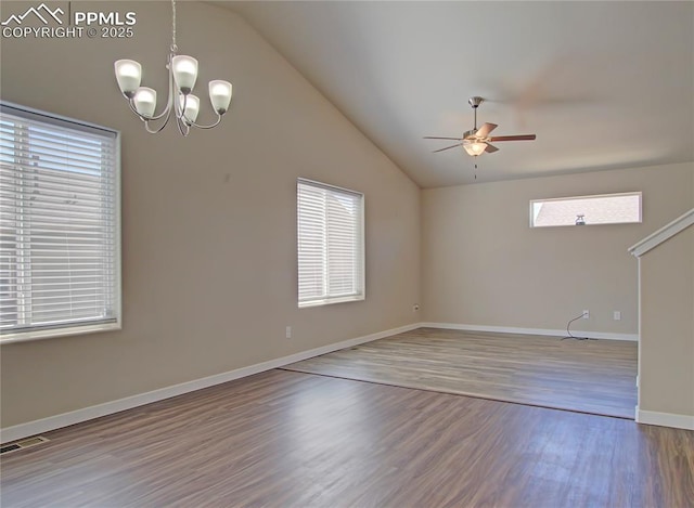 empty room with a healthy amount of sunlight, wood-type flooring, ceiling fan with notable chandelier, and lofted ceiling