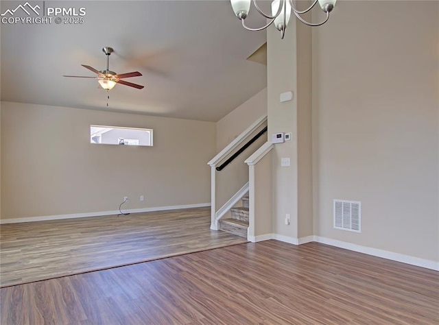 unfurnished living room with ceiling fan with notable chandelier and wood-type flooring