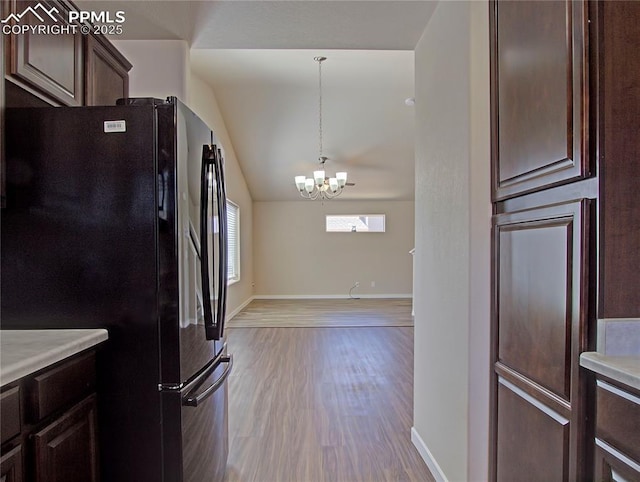 kitchen featuring black fridge, a chandelier, dark brown cabinets, hanging light fixtures, and light hardwood / wood-style flooring