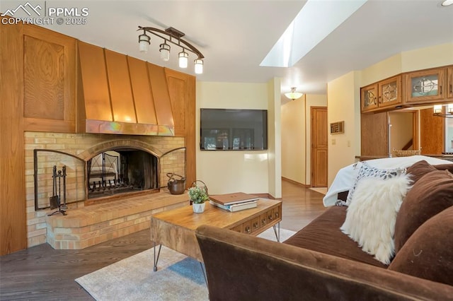 living room featuring a brick fireplace, a skylight, and wood-type flooring