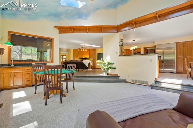 dining room with a high ceiling, sink, and a skylight