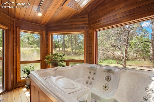 sunroom with wooden ceiling, lofted ceiling with skylight, and a wealth of natural light