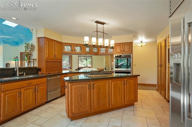 kitchen with sink, hanging light fixtures, stainless steel appliances, a kitchen island, and kitchen peninsula