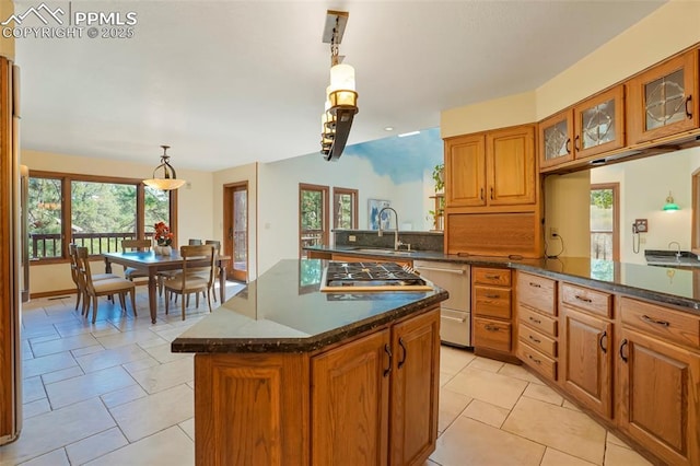 kitchen featuring decorative light fixtures, sink, dark stone countertops, stainless steel gas cooktop, and kitchen peninsula