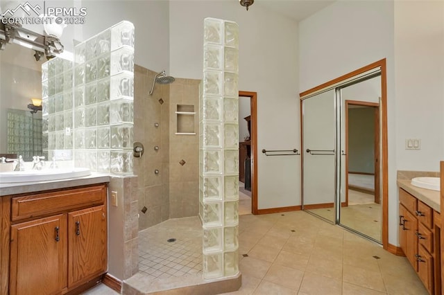 bathroom featuring vanity, tile patterned flooring, and a tile shower