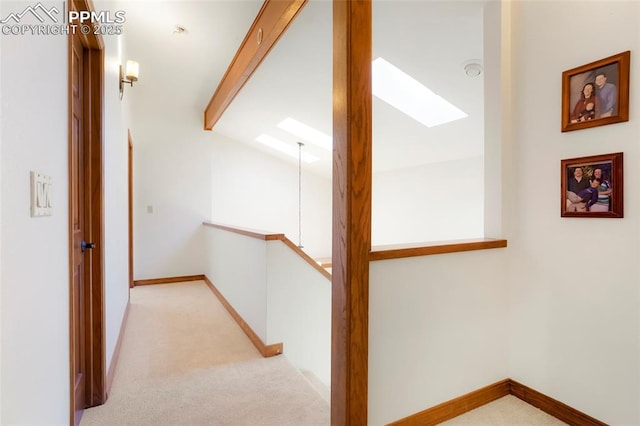 hall featuring lofted ceiling with skylight and light carpet