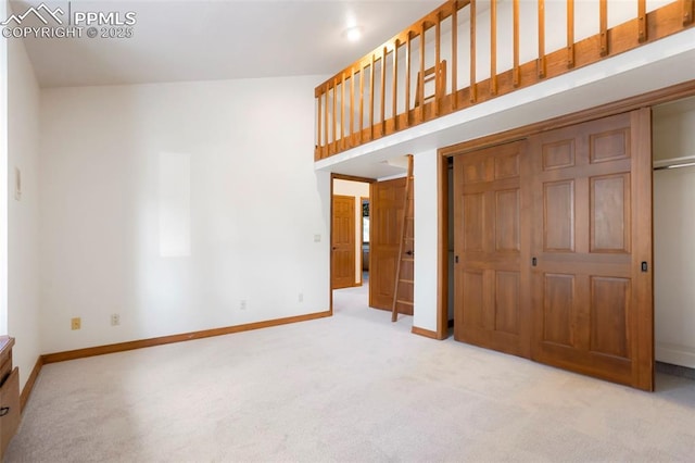 unfurnished bedroom with a high ceiling, light colored carpet, and a closet