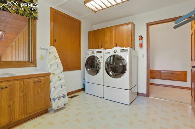 clothes washing area featuring cabinets and washer and clothes dryer