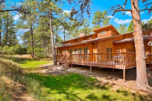 rear view of house with a wooden deck and a yard