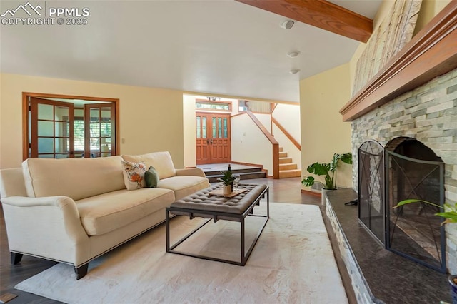 living room featuring french doors, a stone fireplace, and light hardwood / wood-style floors