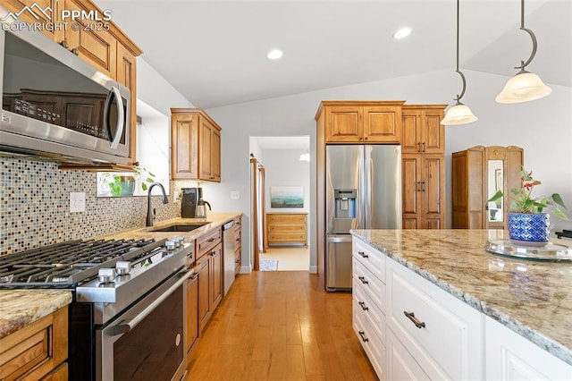 kitchen with pendant lighting, white cabinetry, sink, light stone counters, and stainless steel appliances