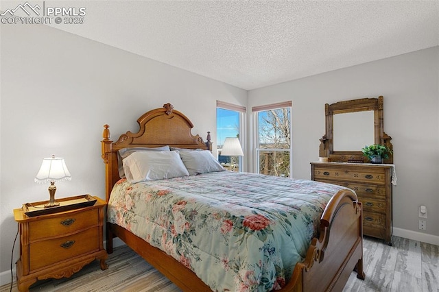 bedroom with a textured ceiling and light hardwood / wood-style floors