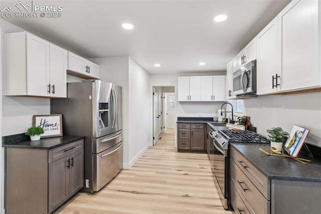 kitchen featuring appliances with stainless steel finishes, sink, white cabinets, and light hardwood / wood-style floors