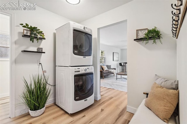 laundry area with stacked washer / dryer and light hardwood / wood-style floors