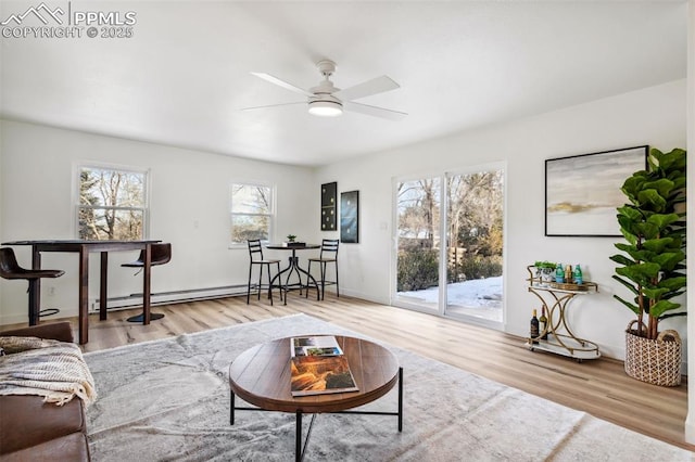 living room with a baseboard heating unit, light hardwood / wood-style floors, and ceiling fan