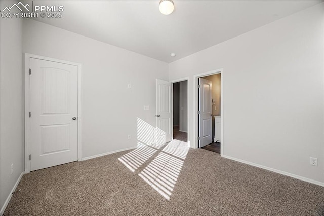 unfurnished bedroom with dark colored carpet and ensuite bath