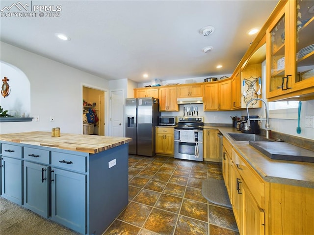 kitchen featuring stainless steel appliances, recessed lighting, butcher block counters, glass insert cabinets, and a sink