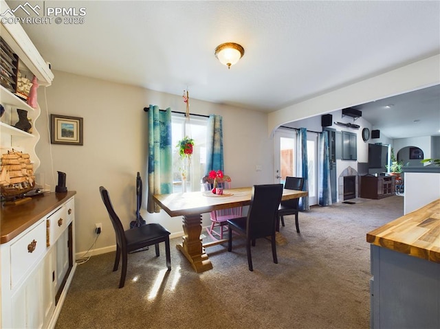 dining room with arched walkways, dark carpet, and baseboards