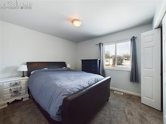 bedroom with dark colored carpet, visible vents, and baseboards