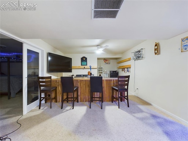 kitchen featuring ceiling fan, a breakfast bar area, a peninsula, visible vents, and light countertops