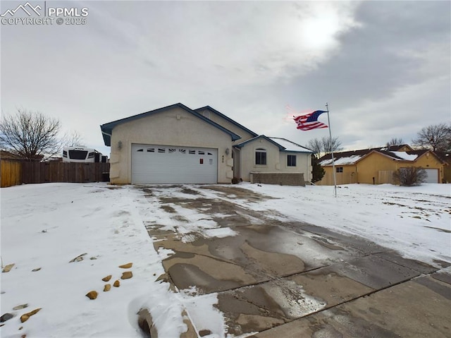 ranch-style home with an attached garage, fence, and stucco siding