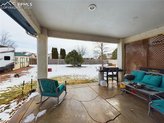 snow covered patio featuring a grill, an outdoor living space, and a fenced backyard