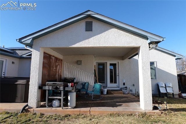 back of property featuring a patio area, a hot tub, and stucco siding