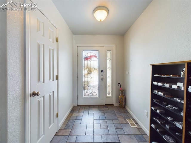 foyer with stone finish flooring, visible vents, and baseboards