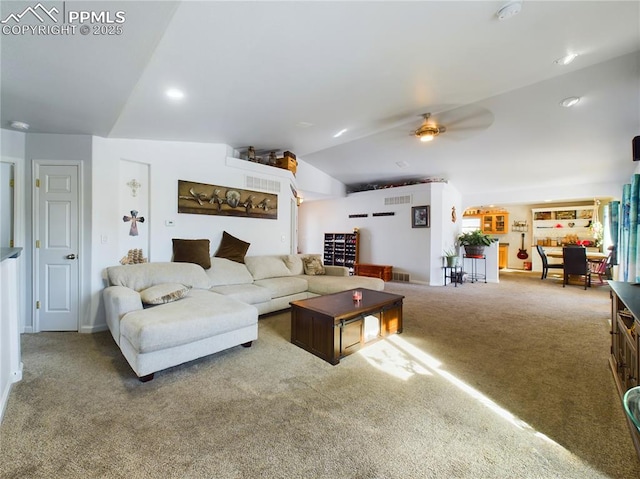 carpeted living area with visible vents, vaulted ceiling, and ceiling fan