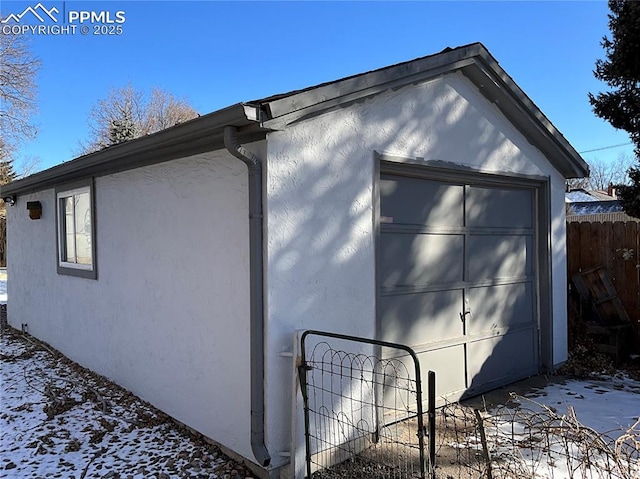 view of snow covered exterior featuring a garage and an outdoor structure