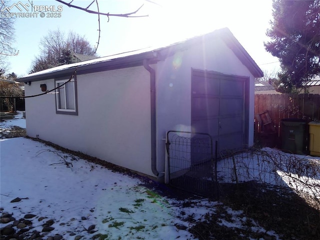 view of snow covered exterior featuring an outbuilding and a garage