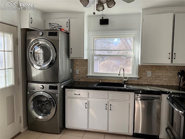 laundry room featuring a healthy amount of sunlight, stacked washer / dryer, sink, and light tile patterned floors