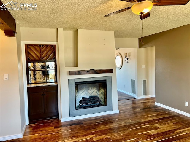 unfurnished living room with dark hardwood / wood-style flooring, ceiling fan, and a textured ceiling