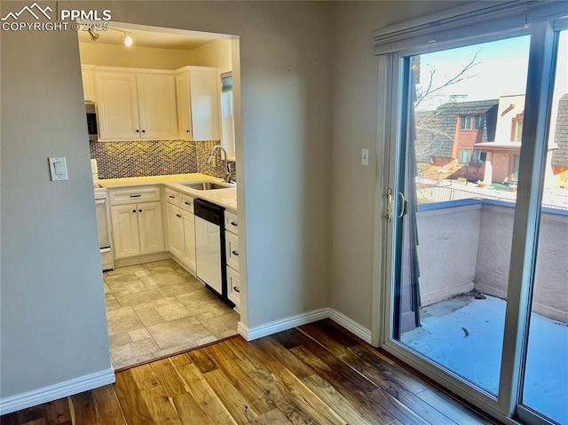 kitchen with appliances with stainless steel finishes, tasteful backsplash, sink, white cabinets, and light wood-type flooring