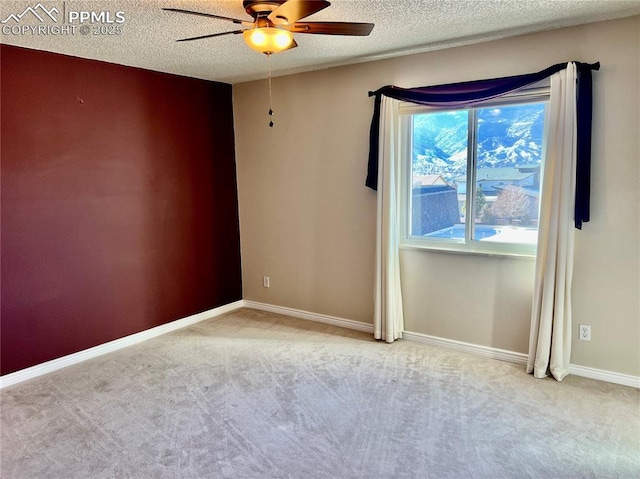 empty room featuring ceiling fan, light carpet, and a textured ceiling